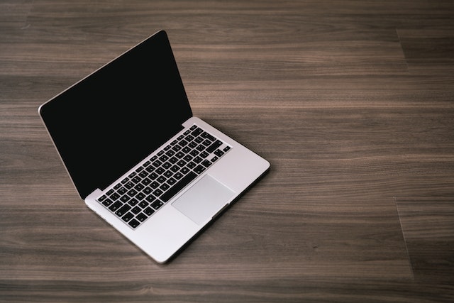 Apple refurbished UK: A black and silver laptop that is off and placed on a brown surface