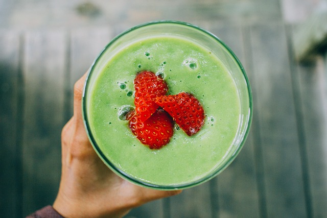 Green smoothie recipe to make on St. Patrick’s Day, with strawberries on top and a blurred background