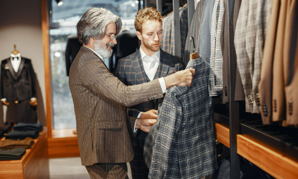 Two men shopping in a men's clothing store for designer tops for men.