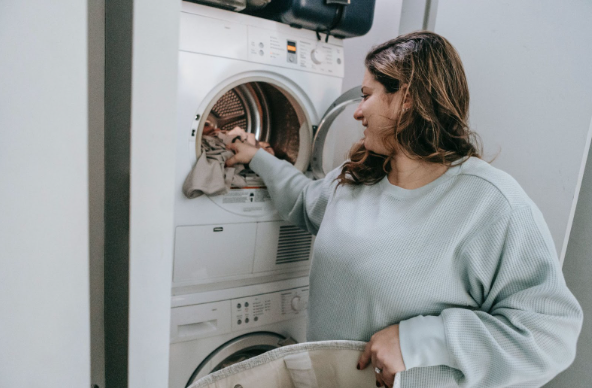 A woman putting her laundry in her Appliances Direct washing machine