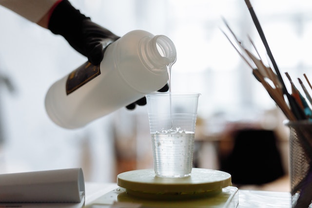 Resin art starter kit: An artist pouring resin into a plastic cup on a scale