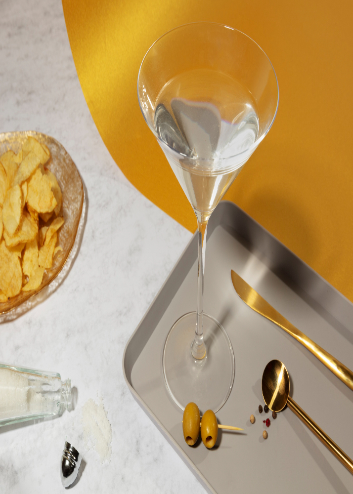 Prosecco cocktails with vodka: Martini glass with prosecco, placed on a table with spoon and knife next to it.