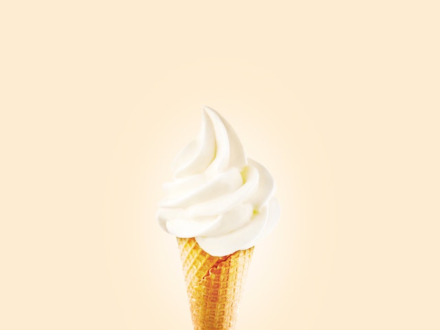 Vanilla ice cream swirl in a cone on a yellow background for National Ice Cream Day