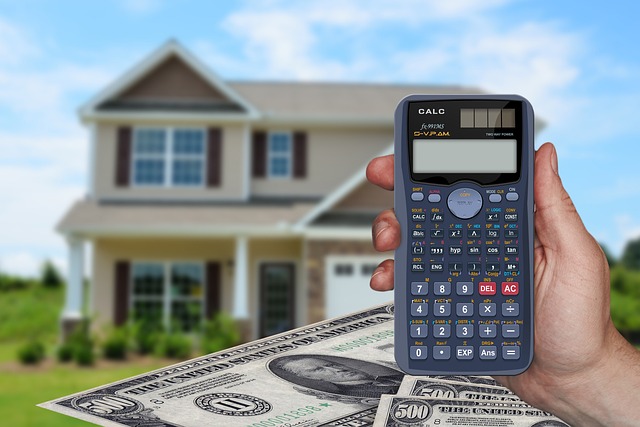 A hand holding a calculator to calculate the Costs For Selling A House and a double-storey house in the blurry background.