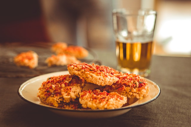 Planning a football party: A white plate with cooked food and a beer glass