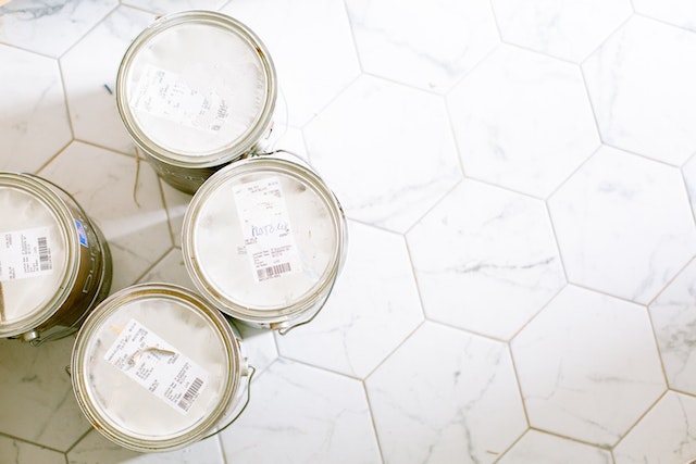 Four cans of Johnstone's trade paint standing on a hexagonal white marble floor