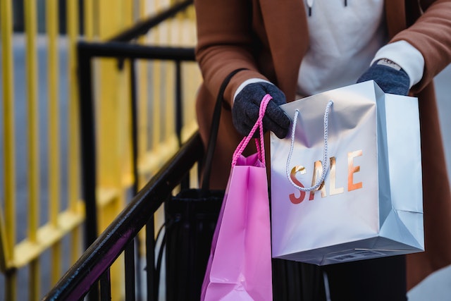 A woman carrying sale shopping bags after shopping and saving during the no spend challenge
