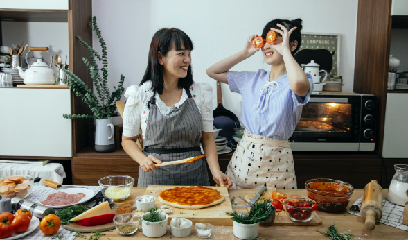 Two women in the kitchen preparing pizza using an Italian pizza recipe