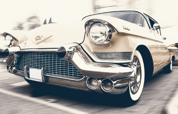 A classic car for sale on eBay that is driving on the road