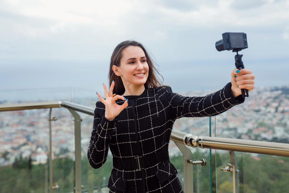 Image: Celebrate World Photography Day: Beautiful lady holding up her camera with a tripod taking a selfie. Celebrate World Photography Day: Beautiful lady holding up her camera with a tripod taking a selfie.