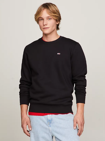 A man wearing a black crew neck sweatshirt from Tommy Hilfiger