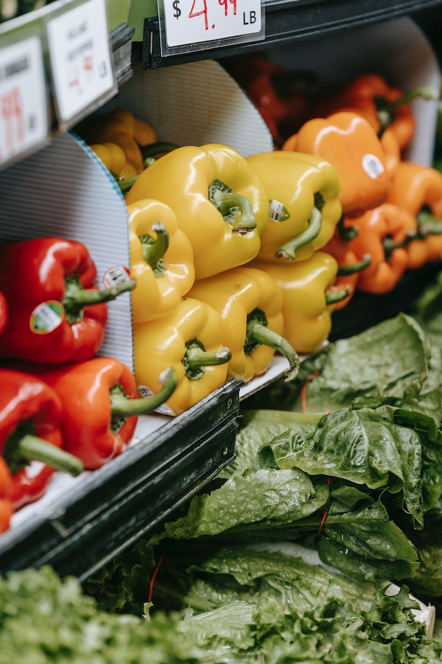 cost of food: Close up view of red, orange & yellow bell peppers and spinach