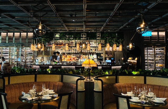 Two restaurants set tables with crockery and a stocked-up bar in the background.