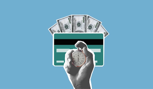A hand holding a stopwatch with a credit card and banknotes behind it