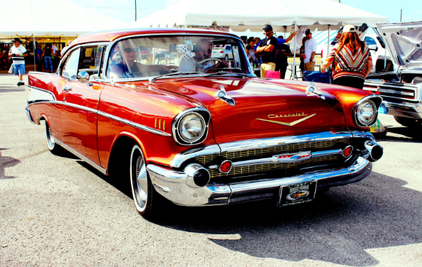 eBay car for sale that is parked at a classic car show with people, cars and food stands in the background.