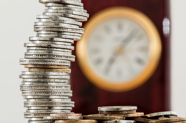 A stack of pennies saved on built-in kitchen appliances with a clock in the background.