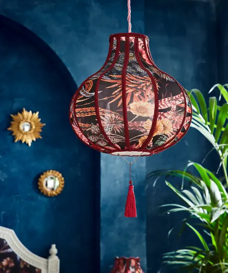 A red floral pendant shade hanging from the ceiling in a room with blue walls