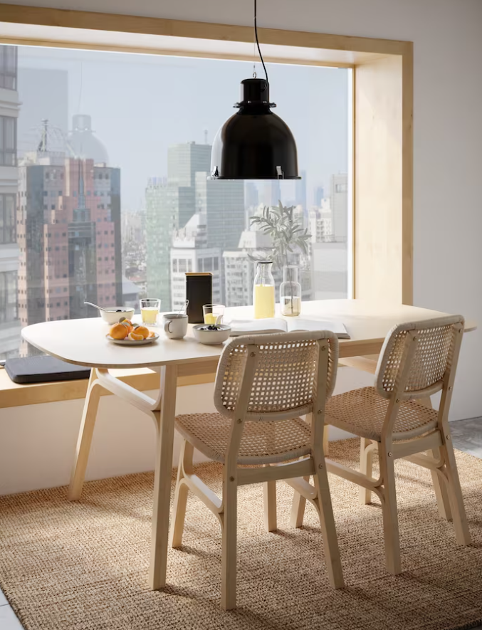 Image: An oak dining table with two chairs standing in front of a window with a view of the city An oak dining table with two chairs standing in front of a window with a view of the city