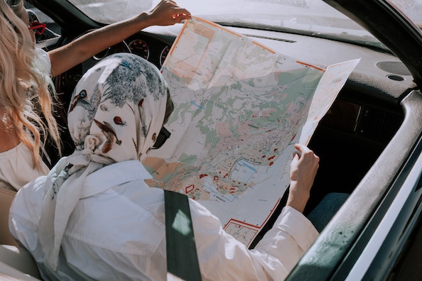 Affordable student travel: Two students looking at a map while sitting in a car