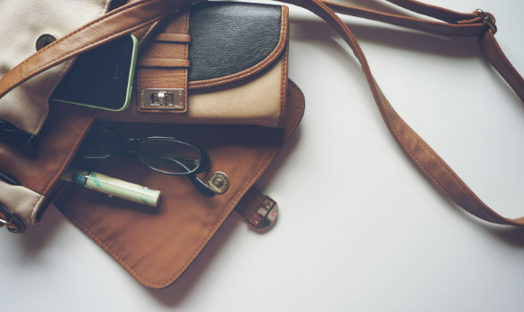 One of the Dorothy Perkins bags placed on top of a table with a purse, makeup and eyeglasses inside.