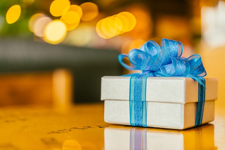 Gift ideas for teachers: A gift box with a blue ribbon on a glossy table