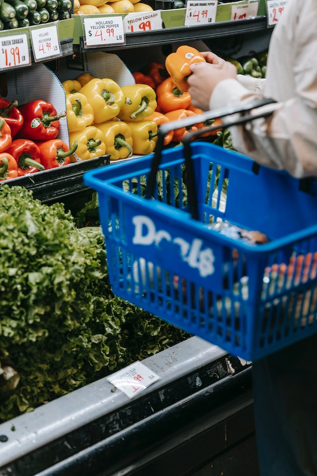 food prices (UK): A person browsing a grocery store’s display of bell peppers and spinach