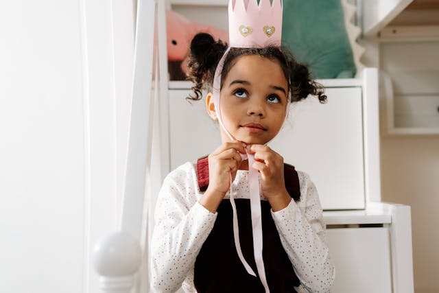 Red Nose Day ideas for schools: a little girl putting on a pink paper crown