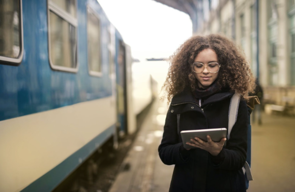 A woman at a train station looking for answers about the Great British Rail sale on her tablet.