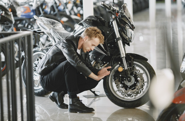 A man sitting next to his motorbike because he is selling it on eBay for motorcycles