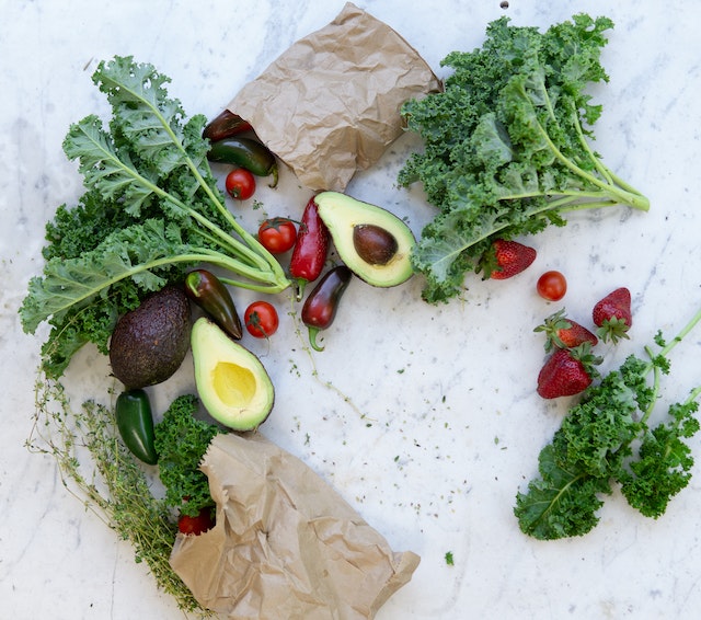Two bags of wonky vegetables laid out across a marble countertop in a circle