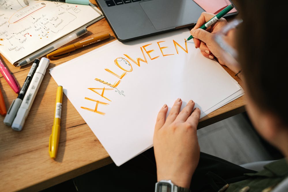 Appropriate Halloween costumes for work: A person in the office writing a Halloween sign