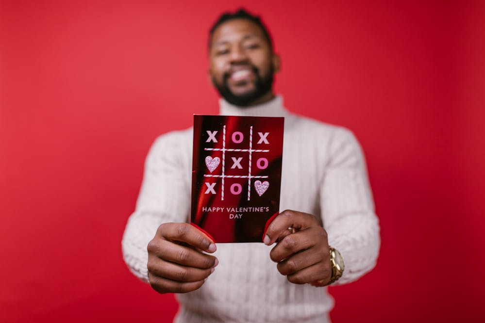 Valentine's Day gift ideas for men: A man holding up a Valentine’s Day card