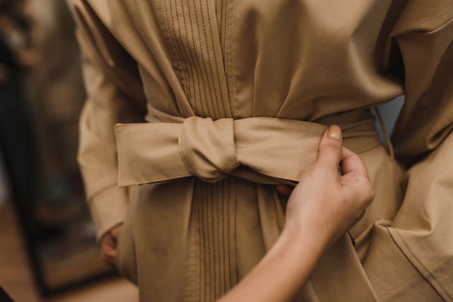 Winter fashion 2026: A person fixing a belt on a brown coat