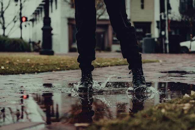 A person wearing waterproof walking shoes and splashing in a rain puddle