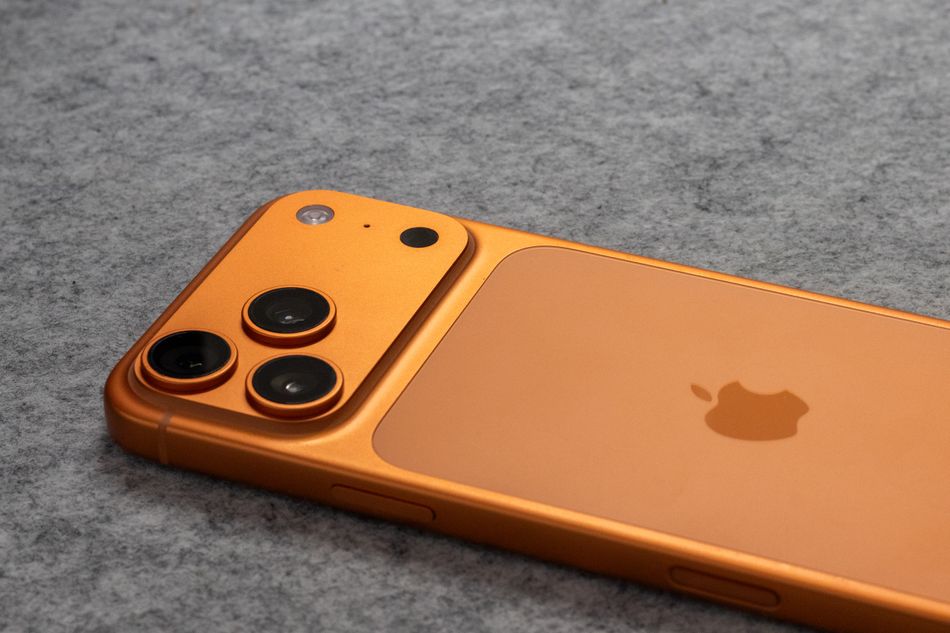Orange Apple iPhone 18 Pro with dual cameras placed on a soft gray fabric surface