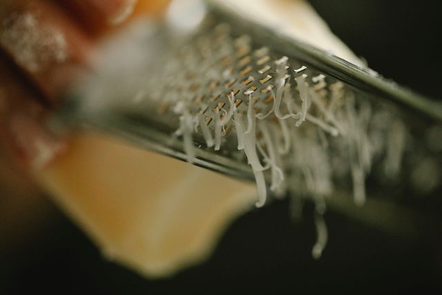 The best Australian cheese being grated on a metal grater in a kitchen environment