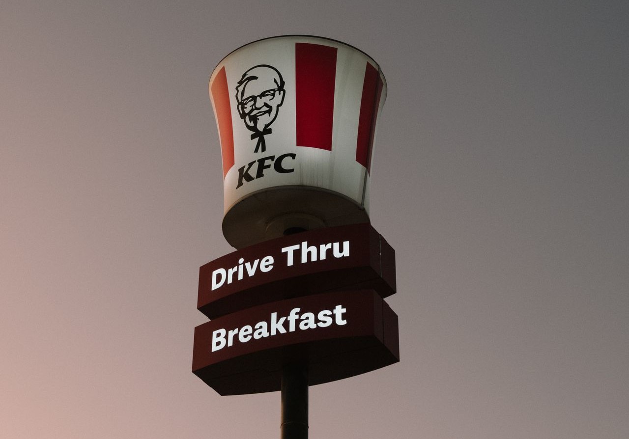 KFC drive-thru sign under a half moon at twilight
