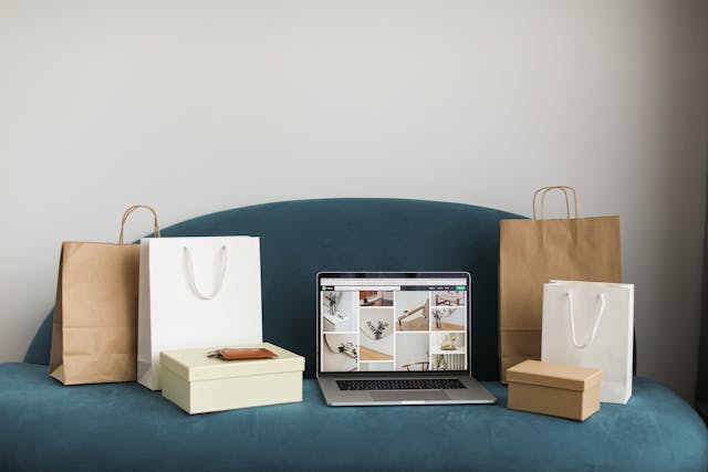 Best Afterpay Day Sales: A laptop next to shopping bags on a blue sofa