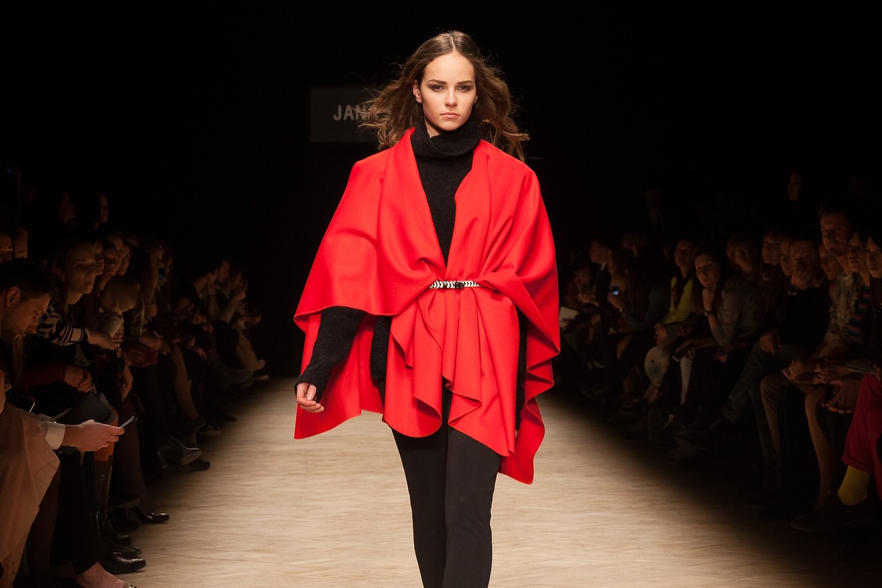 señorita con abrigo rojo sobre una pasarela negra desfilando disponible con un cupón de moda