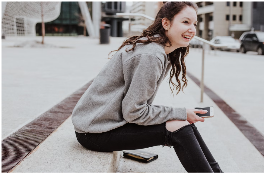 A female student smiling after purchasing baby goods with a firstcry coupon on her mobile phone