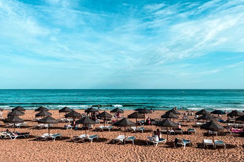 Umbrellas and deck chairs lined up on a beach where you can vacation and save on a holiday booking with a Jet2holidays discount code