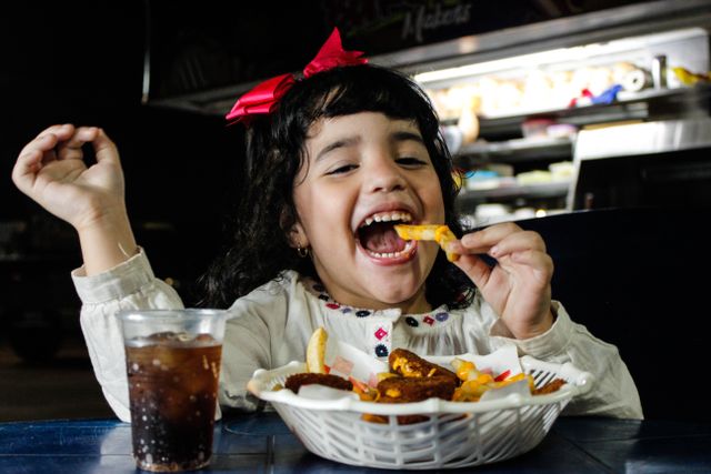 Kids eat for free: A young girl eating fries along with a glass of soda
