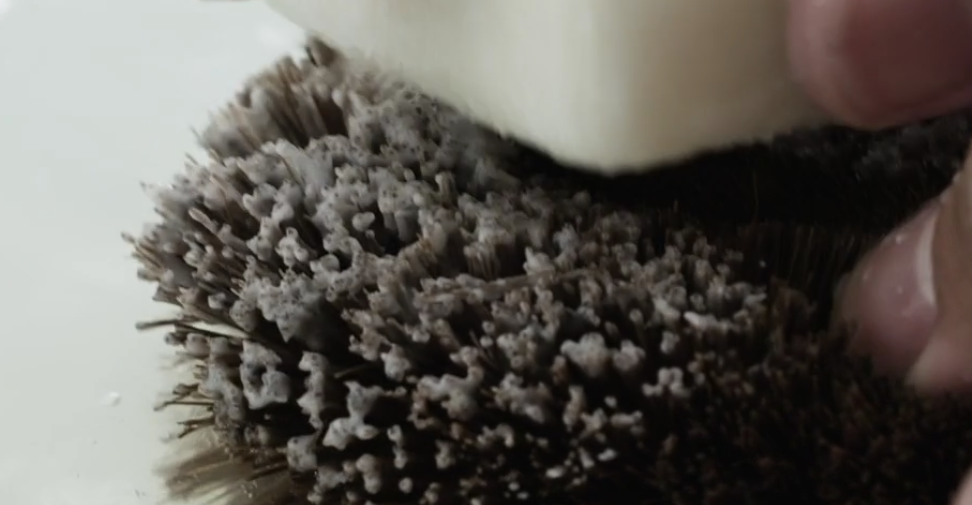 An image of a hand applying soap on a sponge inside water