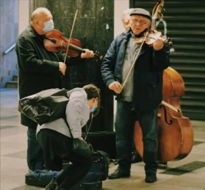 Older men performing with violins and cello from Gear4music in a metro station.