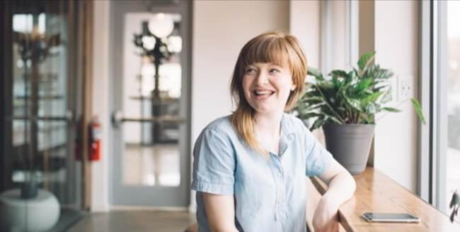 career smarter lady leaning to a window while smiling at a disctance