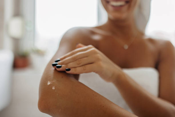 une femme qui applique un crème sur sa peau. elle a un vernis noir sur les ongles. cette crème est disponible à ioma paris avec un code promo ioma paris
