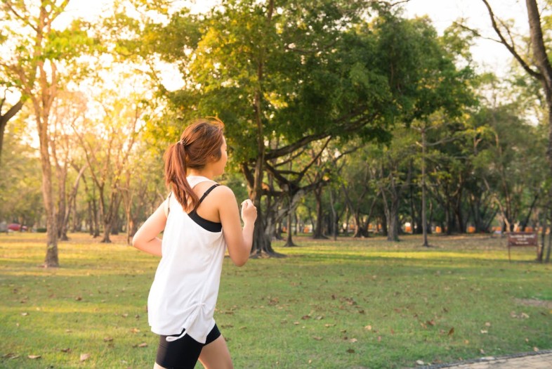 donna che corre in un parco con abbigliamento comprato in offerta grazie ad un coupon Sports Direct