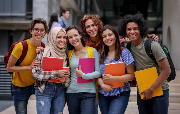 des adolescents dans une cour d'école le jour de la rentrée scolaire. ils tiennent des cahiers et livres dans la main.