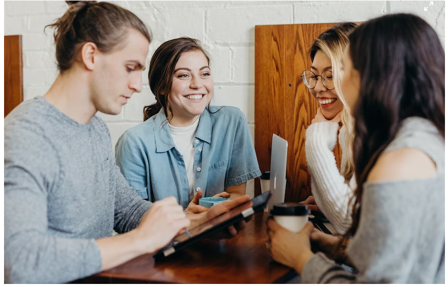 Three female and one male student browsing for a SHEIN promo code on a laptop and iPad to shop