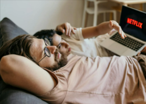 Man and woman lying in bed watching netflix